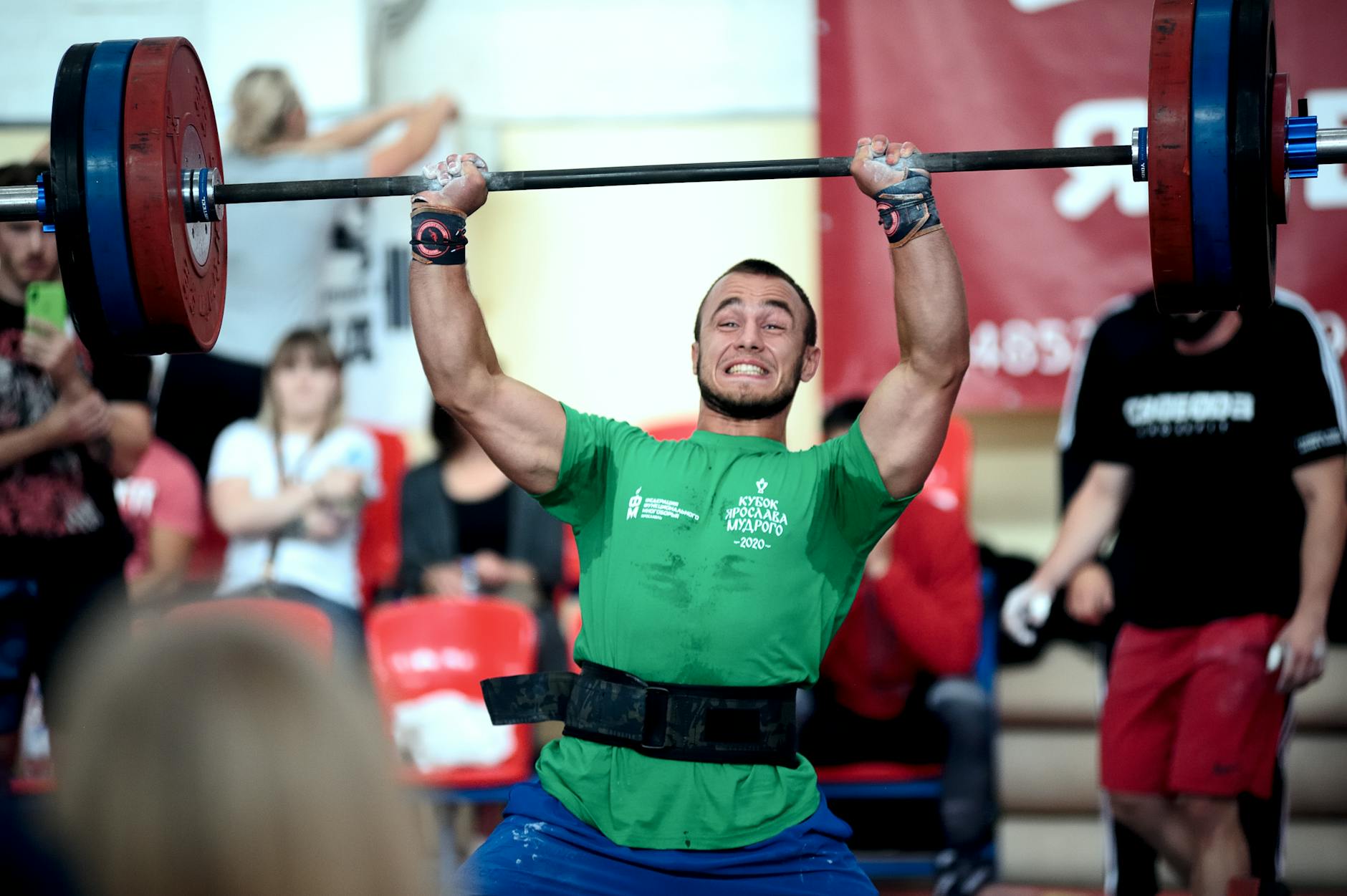 Athlete mid-rep with chalked hands lifting a heavy barbell