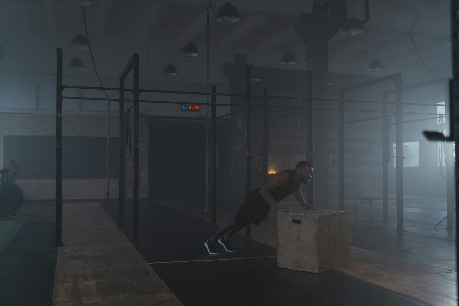 Athlete pushing a heavy sled on turf in a dark gym