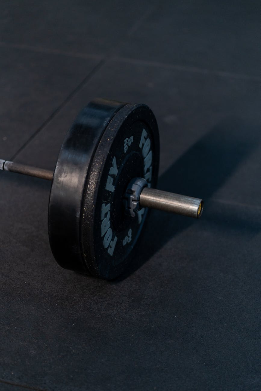Calibrated weight plates on a barbell in a dark gym