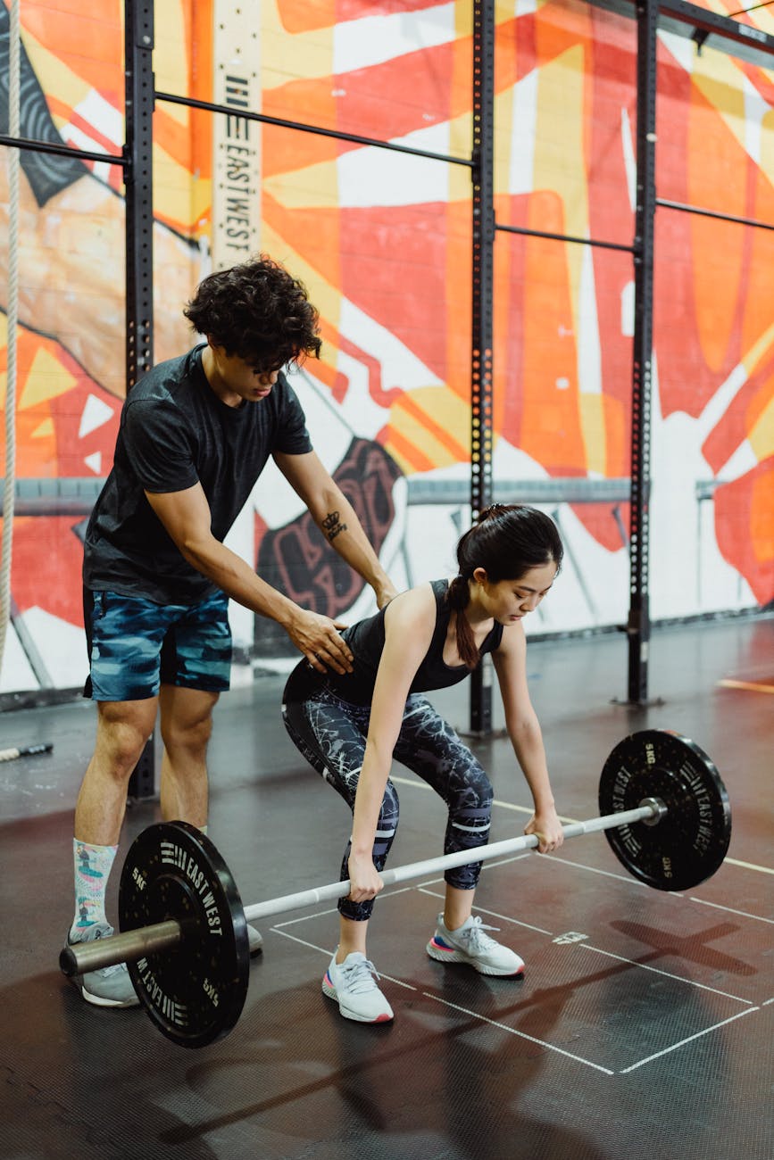 Coach adjusting lifter's form on a squat rack