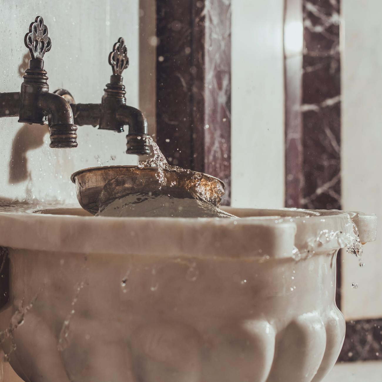 Elegant marble washbasin with water flowing from ornate faucet, showcasing luxury and hygiene.