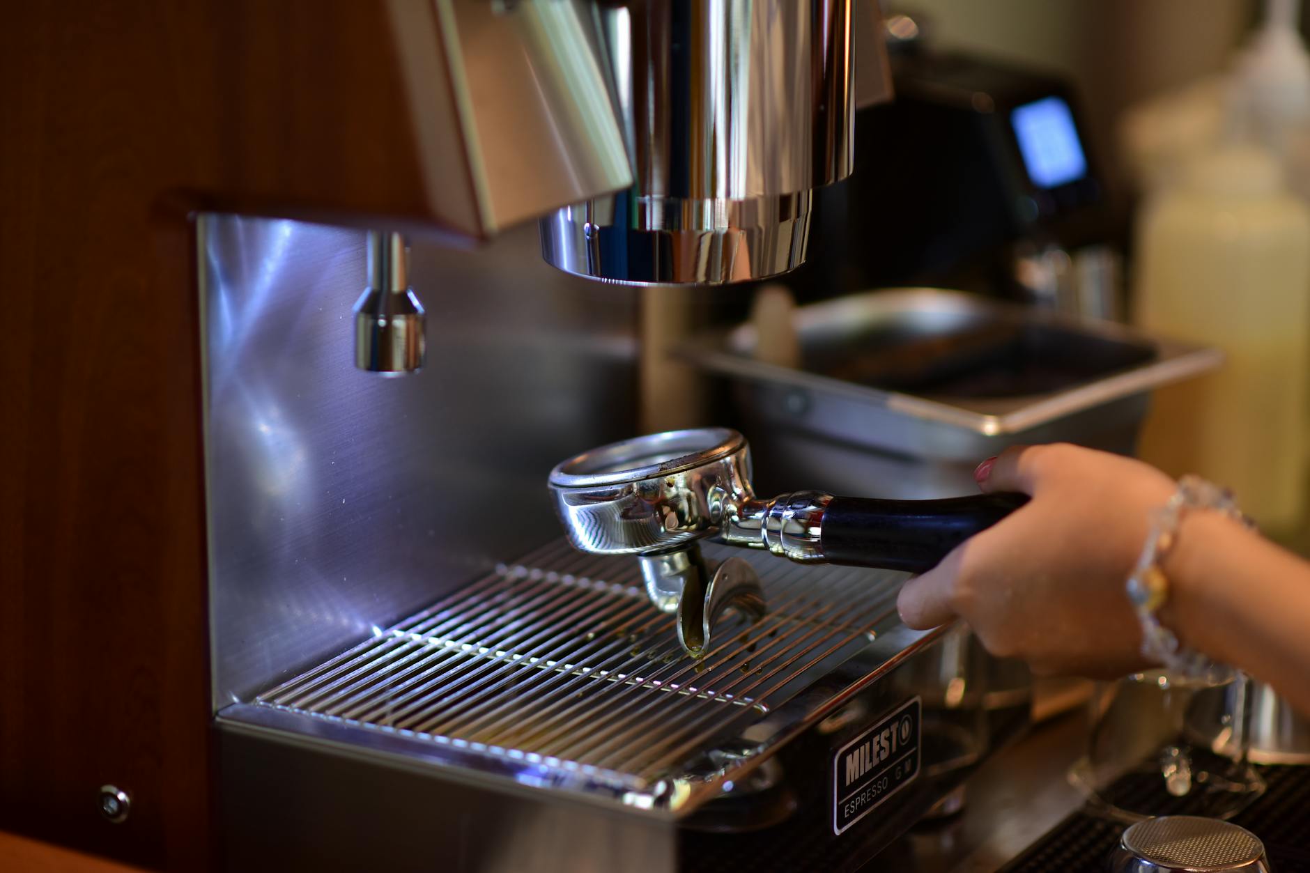 Barista pulling an espresso shot on a shiny machine.