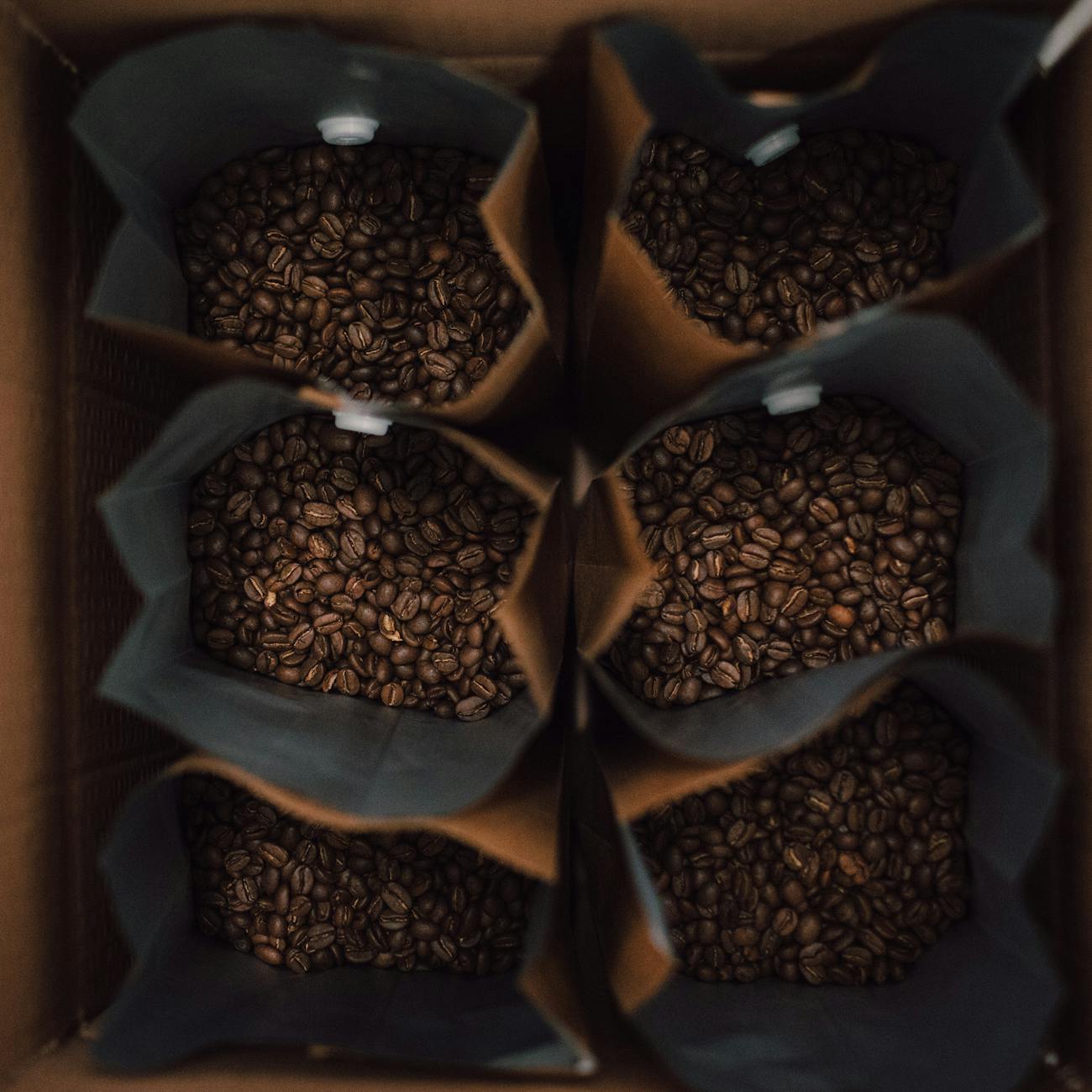Bags of freshly roasted Olen coffee beans on a wooden shelf.